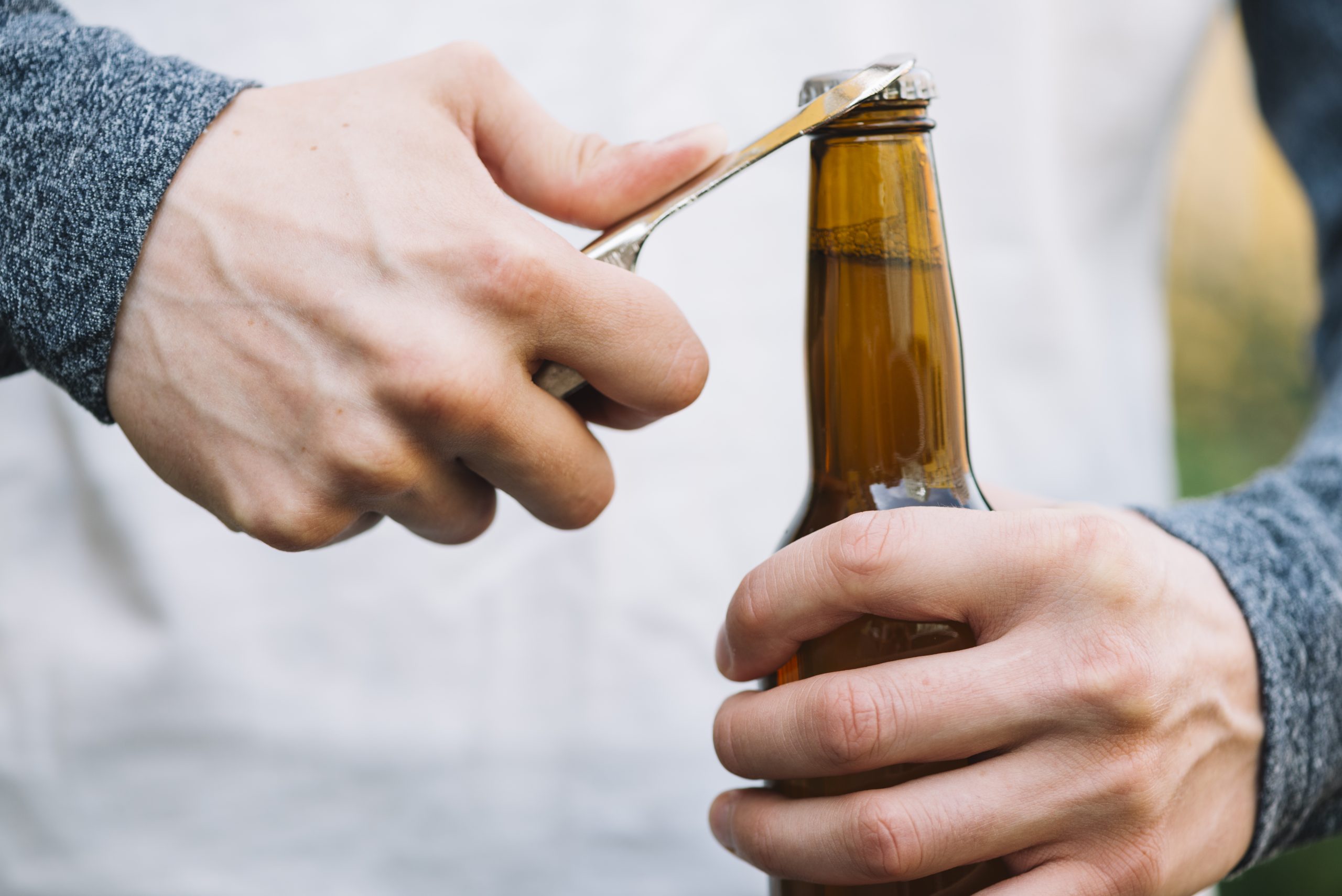 fľaša s alkoholom, ktorú niekto otvára
