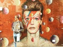 mladý muž stojaci pred plagátom Davida Bowieho