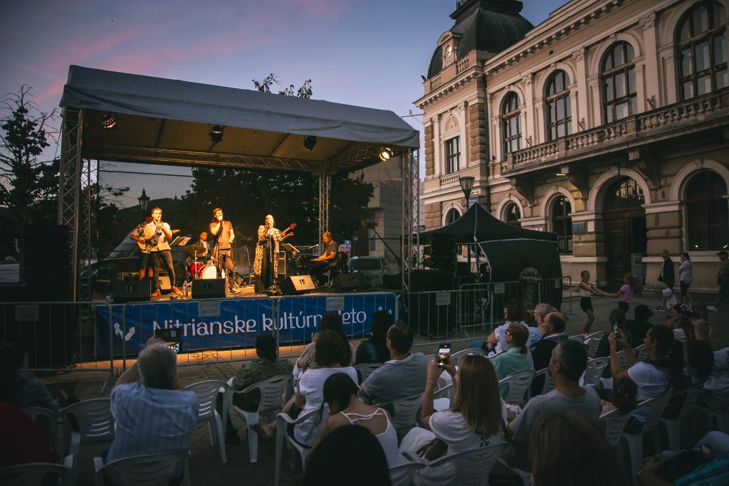 Vystupujúca kapela na pódiu s množstvom sledujúcich divákov