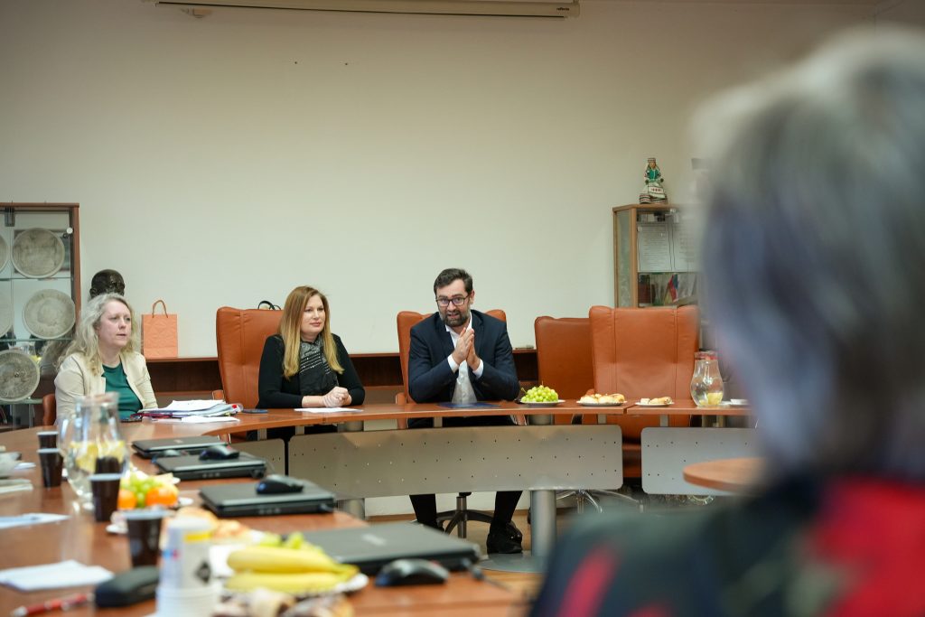 dve ženy a muž sedia za stolom v zasadačke