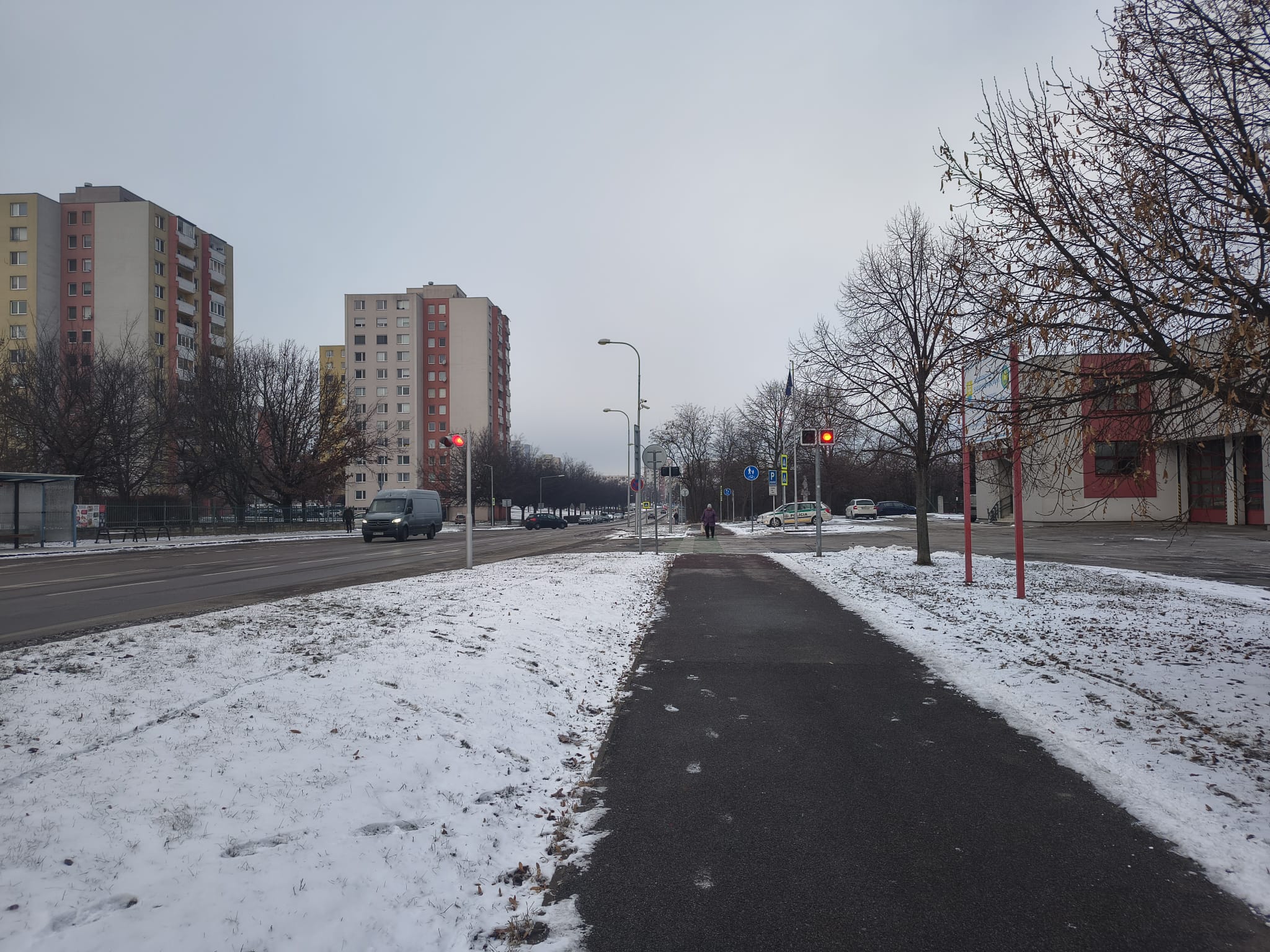 pohľad na zasnežený chodník pri hasičskej stanici, kde je umiestnený špeciálny semafor umožňujúci výjazd hasičským autám